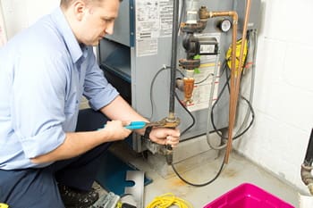 Technician repairing residential water heater system.